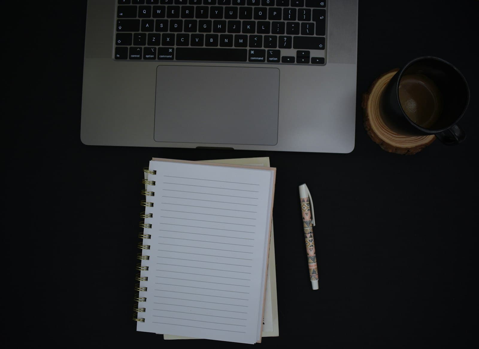 A blank notebook and pen beside a laptop — write the five answers down before you decide