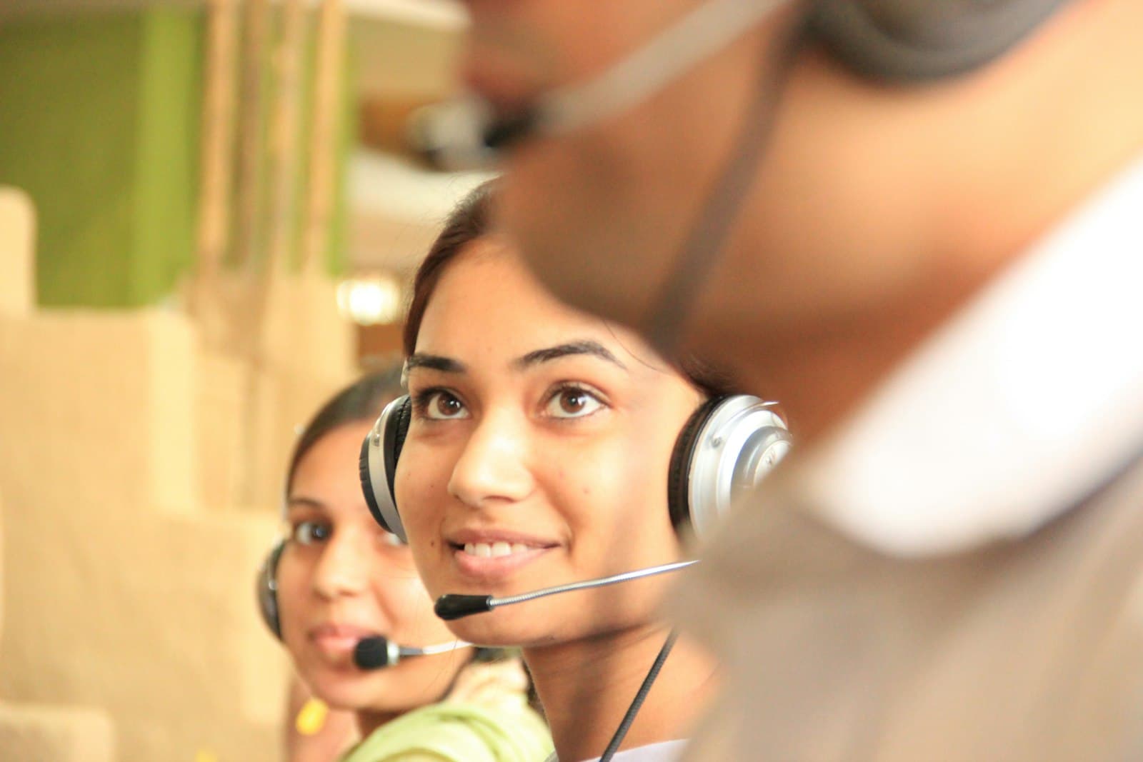 Two front-desk staff on headsets fielding calls at once — the inbound overload a first agent is built to absorb