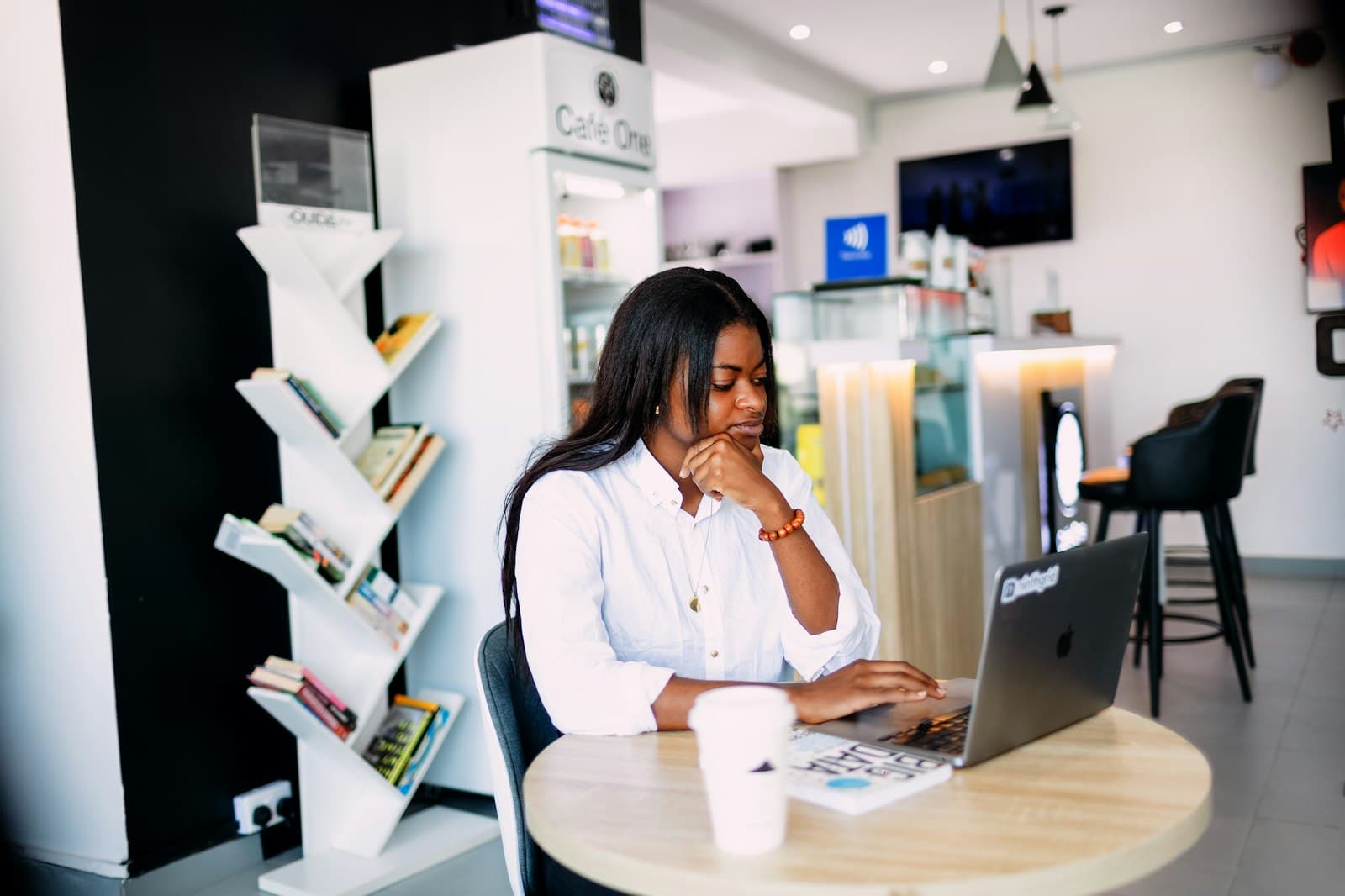 A business owner at her counter, thinking it over on a laptop